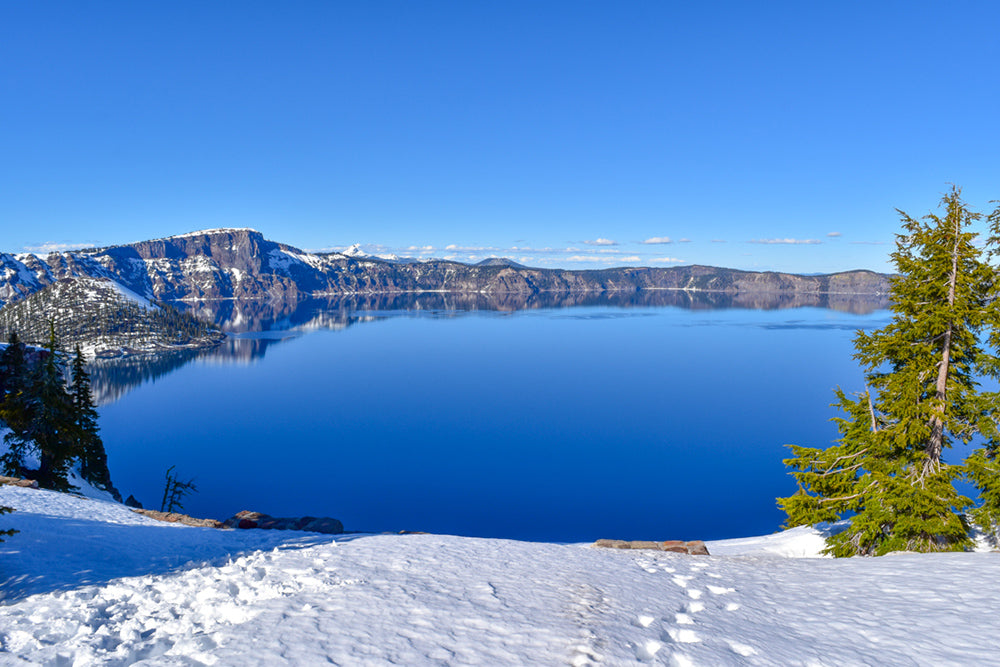 This is a photo of Crater Lake National Park in Oregon. It was taken at the end of March 2022. It was very special to see the lake covered in snow on this sides and on a sunny day.